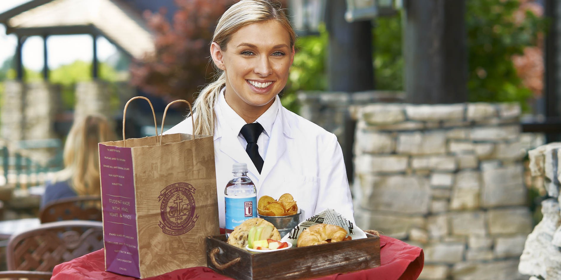 Student server carrying a to-go tray of food