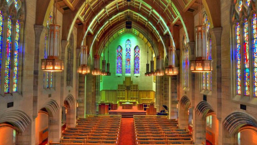 The chapel as seen from inside lit by sunlight through the stain glass windows and ornate lamps.