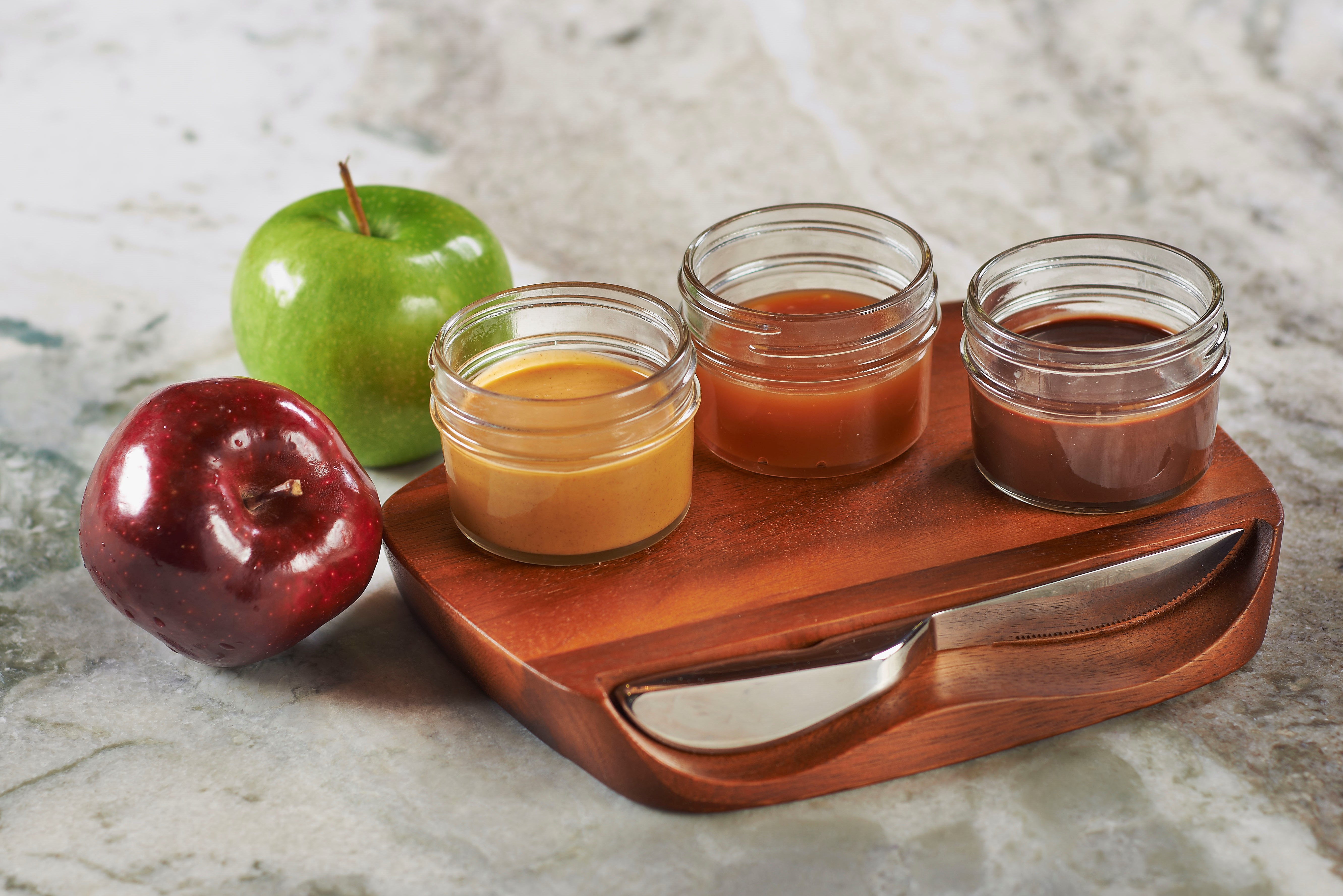 Apples with jars of caramel, chocolate, and peanut butter.