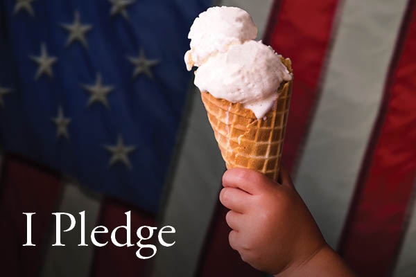 Child holding ice cream cone in front of American flag