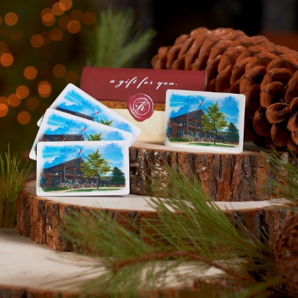 Several Keeter Center gift cards fanned out next to pine cones with a Christmas Tree in the background.